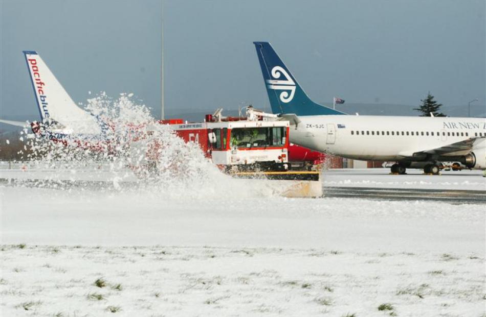 A fire truck fitted with a snow plough clears a section of runway at the airport yesterday...