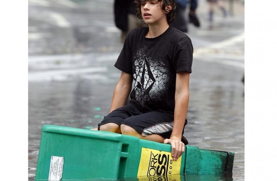 A boy floats on a newspaper box in a flooded street in the Soho section of Manhattan, New York,...