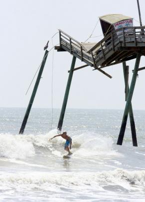 A surfer passes the broken end of the Bogue Inlet Fishing Pier in Emerald Isle, North Carolina...