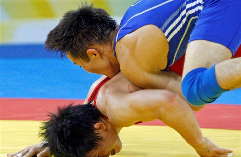 China's Sheng Jang wearing red wrestles with Kazakhstan's Nurbakyt Tengizbayev during their 60kg...