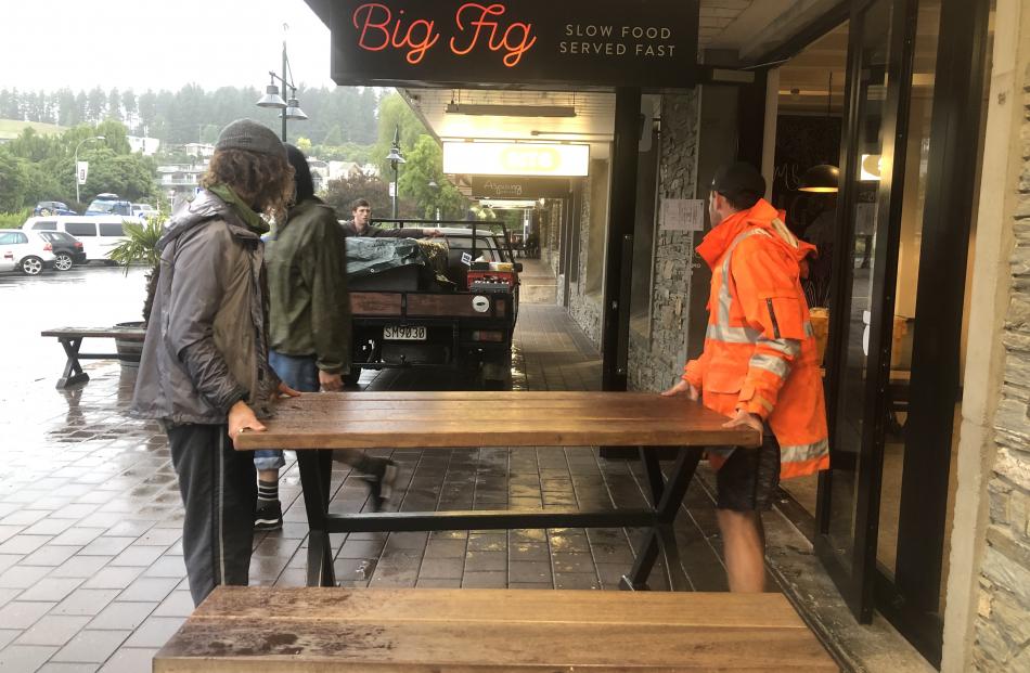 Volunteers move The Big Fig restaurant outdoor seating after the contents of the restaurant had been packed and moved out overnight. Photo: Kerrie Waterworth