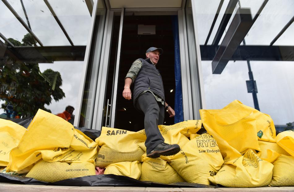 Mark Sanders from the sports shop Southern Wild in Wanaka steps over his sandbagged front door to...