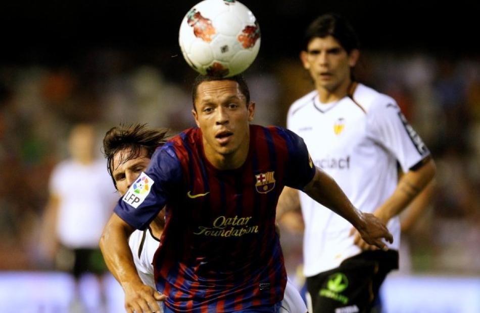 Barcelona's Adriano heads the ball past Valencia's Pablo Piatti and Ever Banega (R) during their...