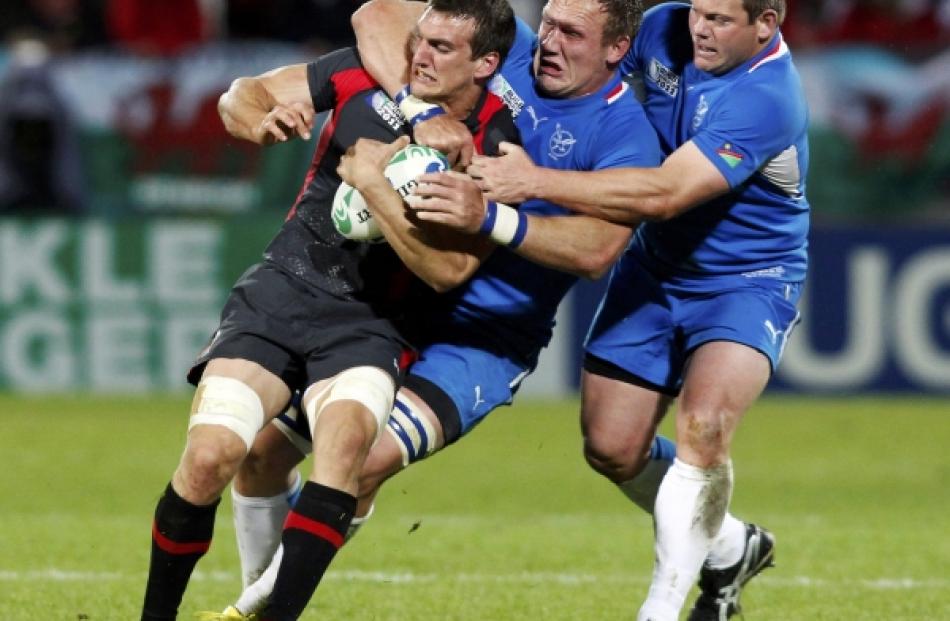 Namibia's Heinz Koll (centre) and Hugo Horn tackle Wales captain Sam Warburton (L) during their...