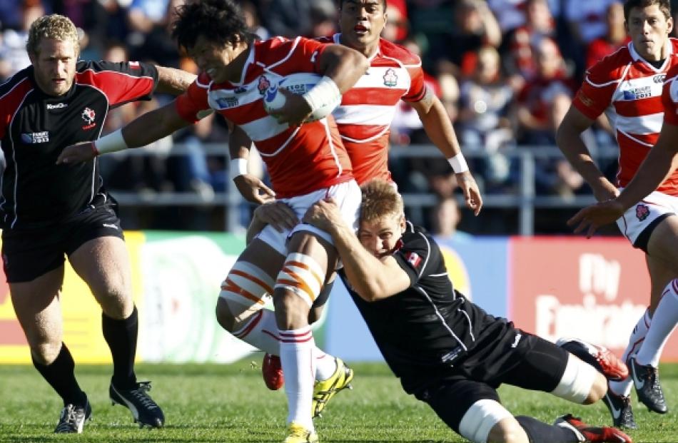 Canada's Chauncey O'Toole (right) tackles Japan captain Takashi Kikutani during their Rugby World...