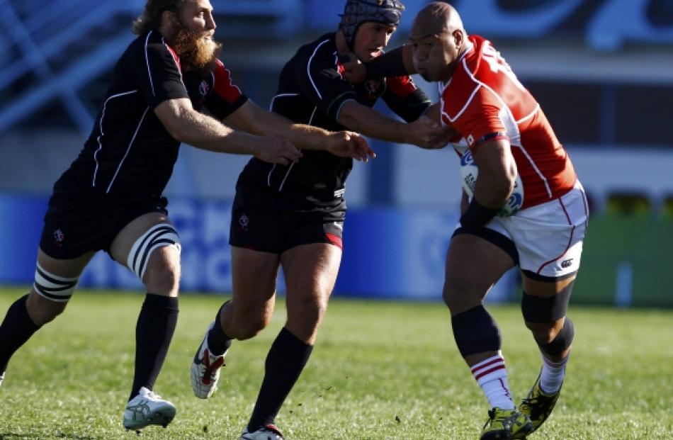 Canada's Ryan Smith (centre) tackles Japan's Alisi Tupuailai (right) during their Rugby World Cup...