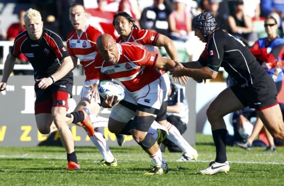 Canada's Ryan Smith (right) tackles Japan's Alisi Tupuailai (C) during their Rugby World Cup Pool...
