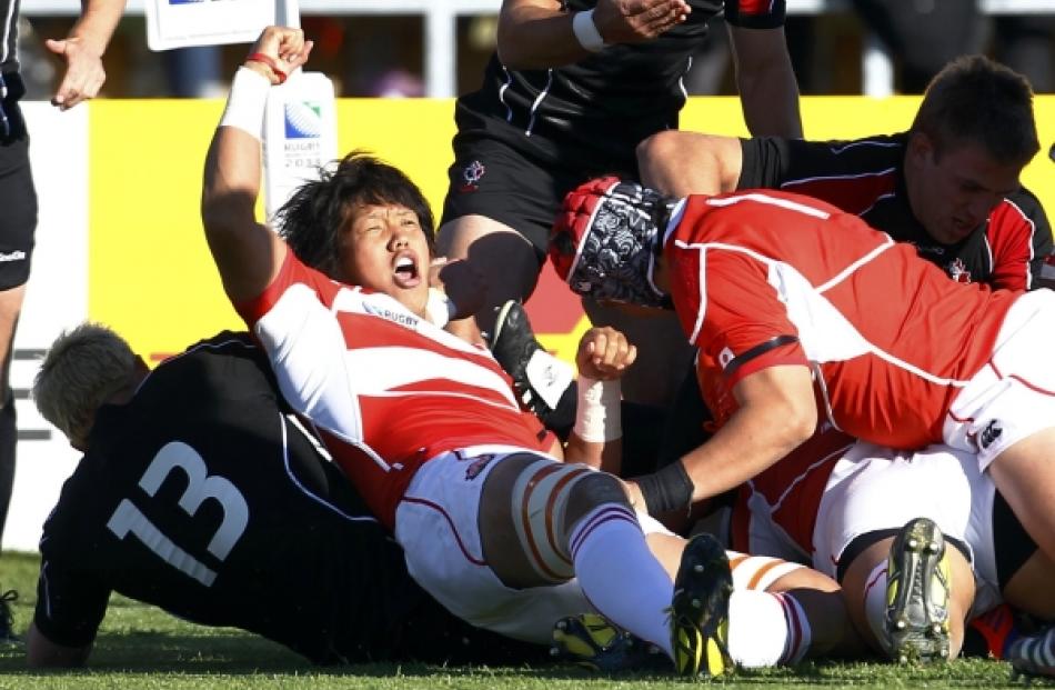 Japan captain Takashi Kikutani (second from left) celebrates his team's try during their Rugby...
