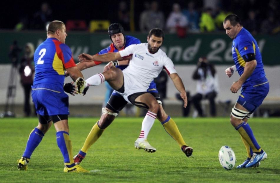 Georgia's Merab Kvirikashvili (centre) fights for the ball with Romania's Mihai Macovei during...
