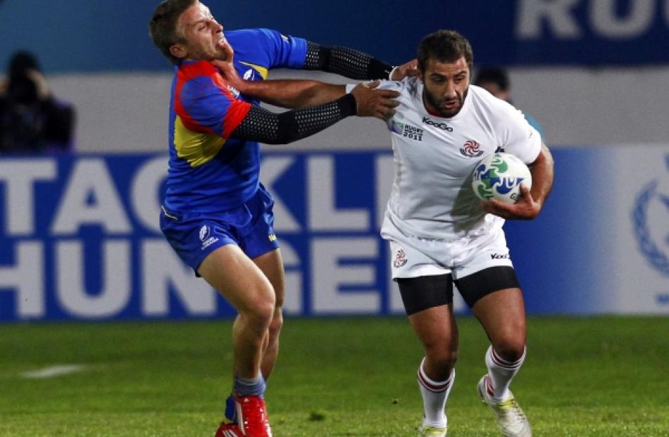 Georgia's Merab Kvirikashvili (right) fends off Romania's Florin Surugiu during their Rugby World...
