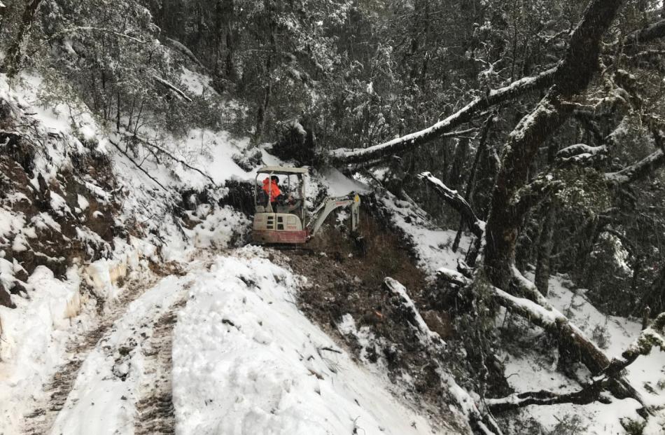 A Nelmac digger operator carves out a rocky hillside track in the snow. PHOTO: TOM WOODWARD-NELMAC