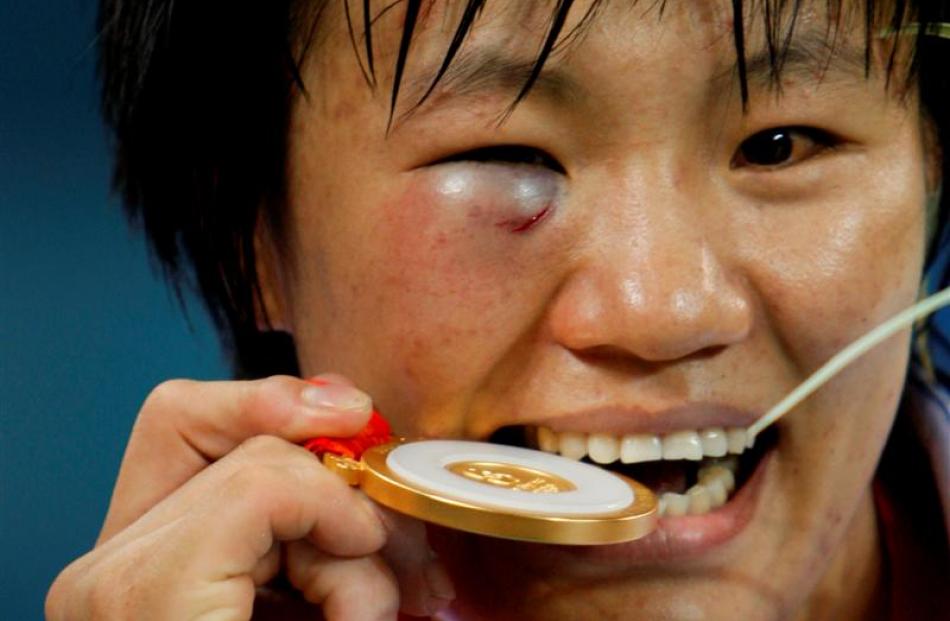 Gold medalist Yang Xiuli of China bites her medal at the suggestion of photographers at the...