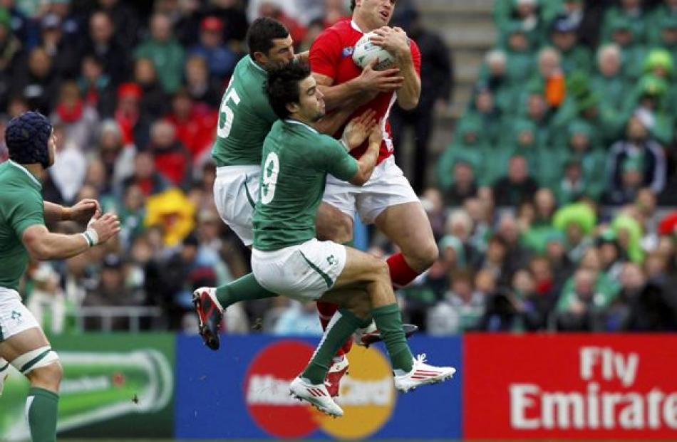Wales' Jamie Roberts (right) takes a high ball against Ireland's Rob Kearney (left) and Conor...