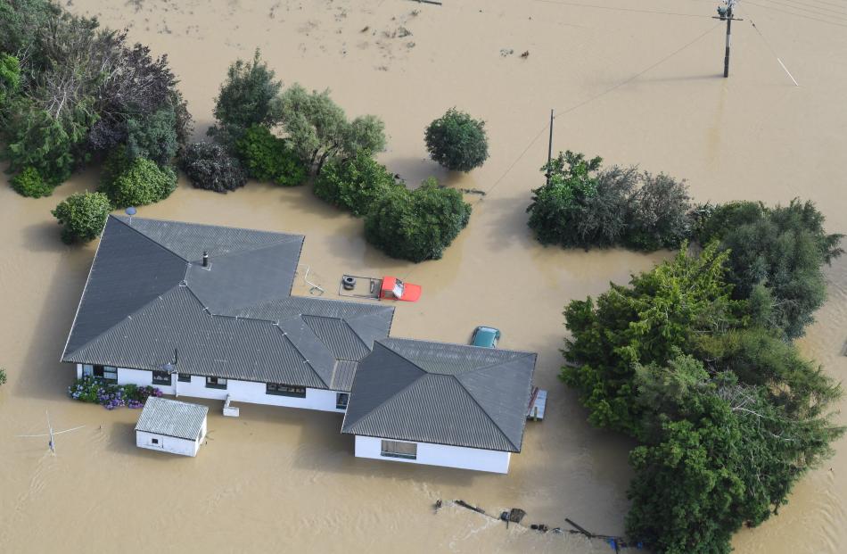 A utility vehicle sits in front of a flooded house, where it was left as the water rose. 