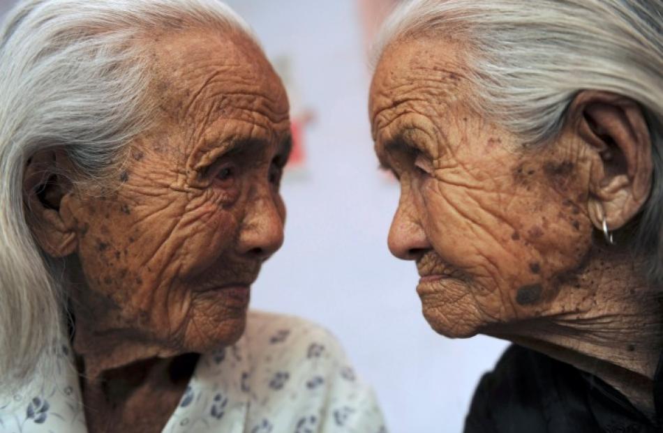 Chinese 104-year-old twins Cao Xiaoqiao (R) and her elder sister Cao Daqiao look at each other on...