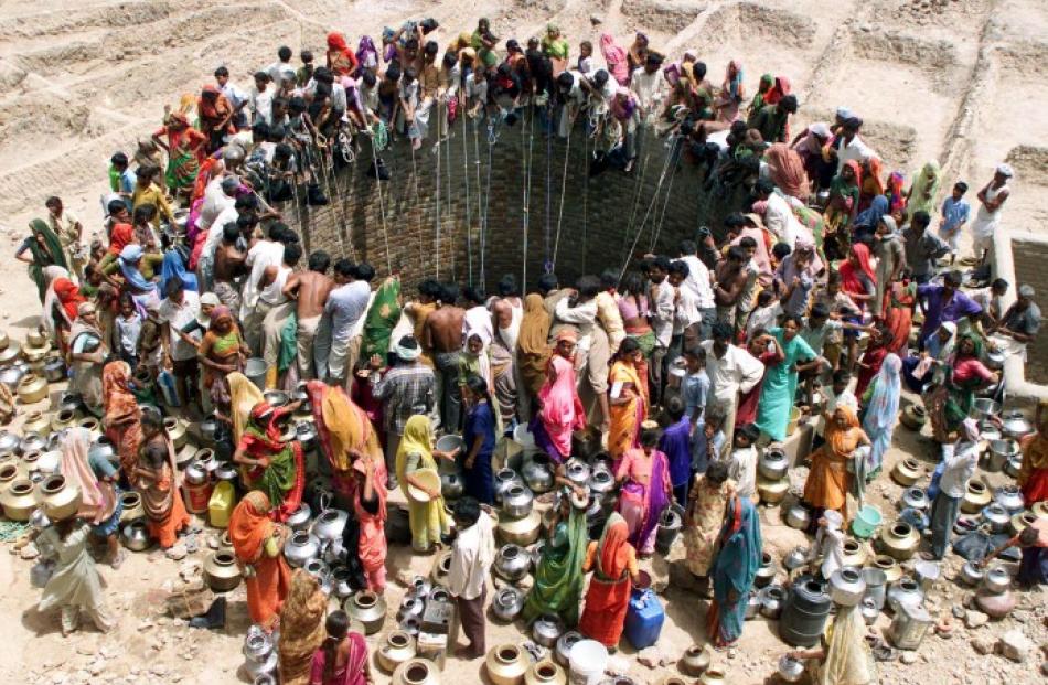 People gather to get water from a huge well in the village of Natwarghad in the western Indian...