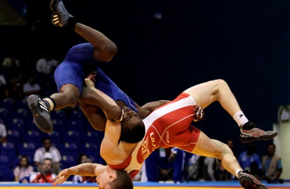 Yowlys Bonne (blue) of Cuba pins Canada Ryley Walker during their men's freestyle 60kg wrestling...