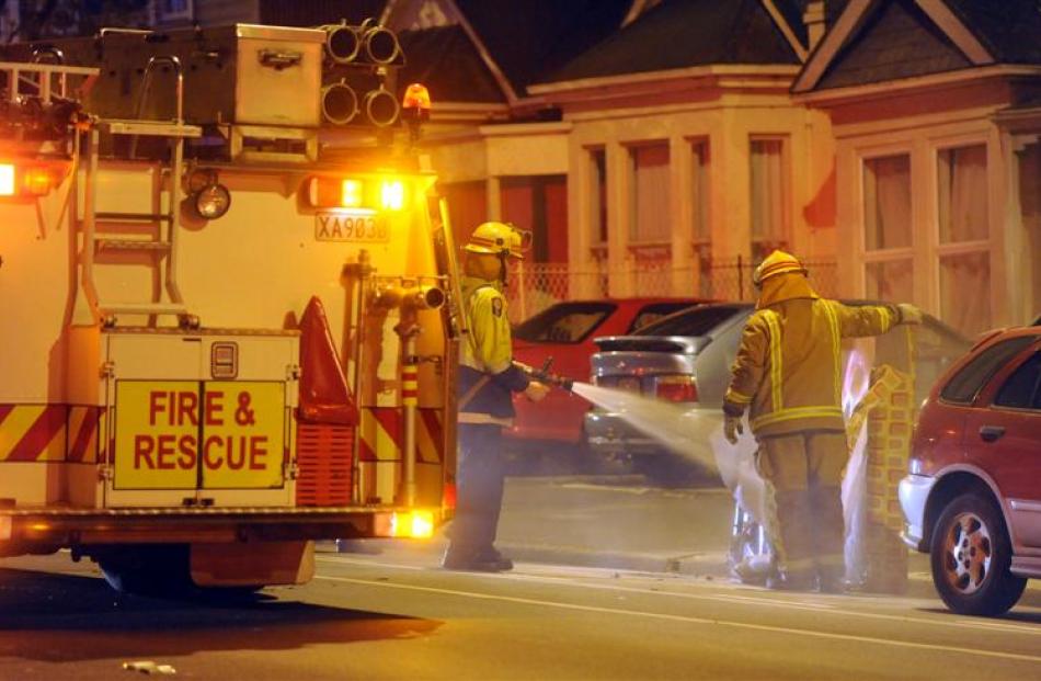 Firefighters do some preventive soaking on a burning mattress after it was removed from the...