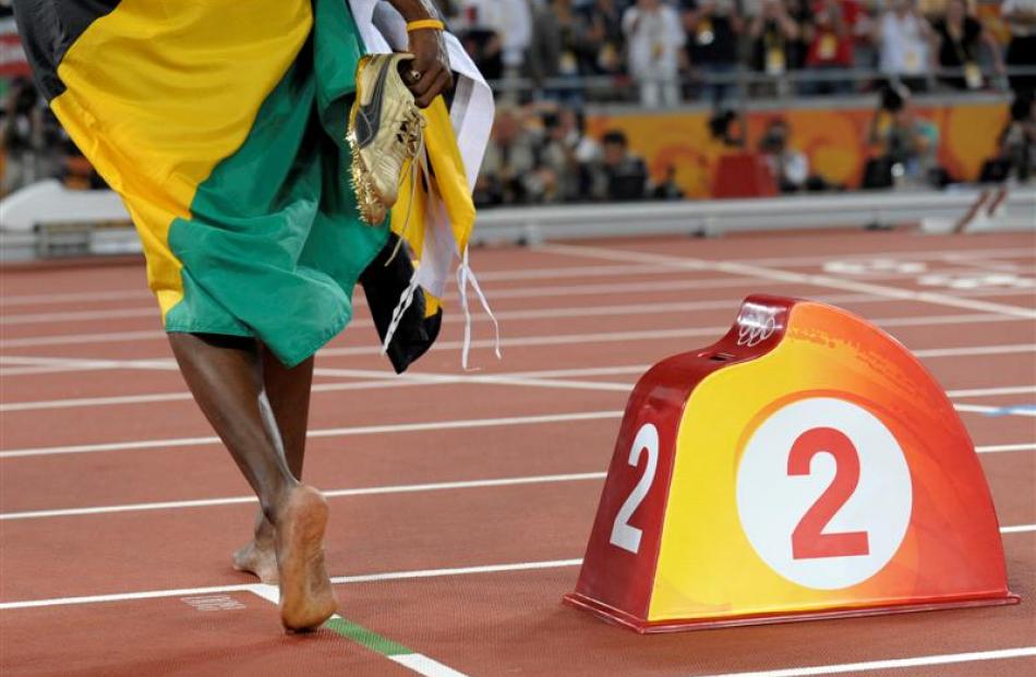 Jamaica's Usain Bolt leaves the track barefoot after winning the men's 200m final with a world...