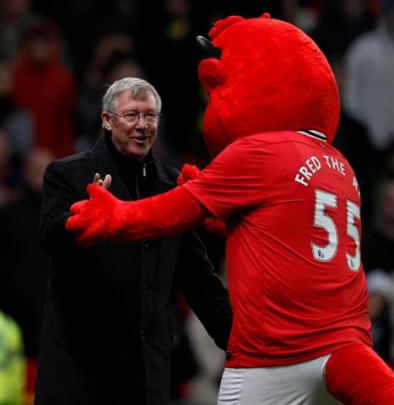 Manchester United's manager Alex Ferguson is greeted by club mascot Fred the Red before their...
