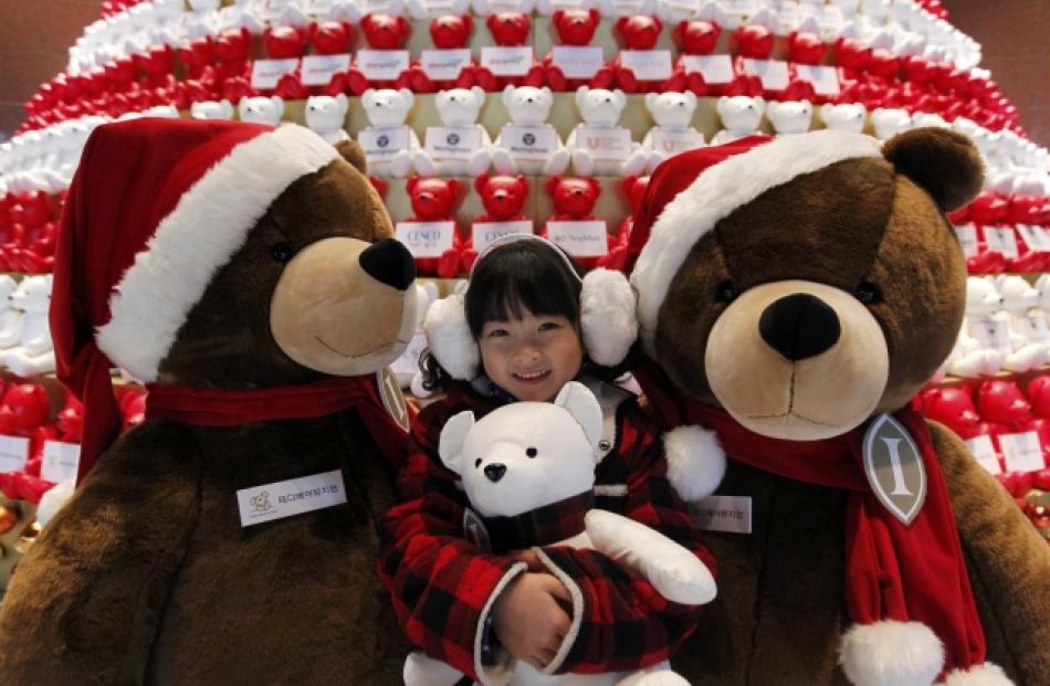 A girl poses for photographs in front of a Christmas tree decorated with Teddy bears at Grand...