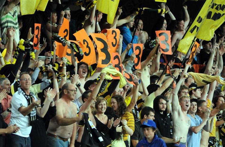 The crowd shows its delight after the Phoenix scores its second goal.  The "3" signs being held...