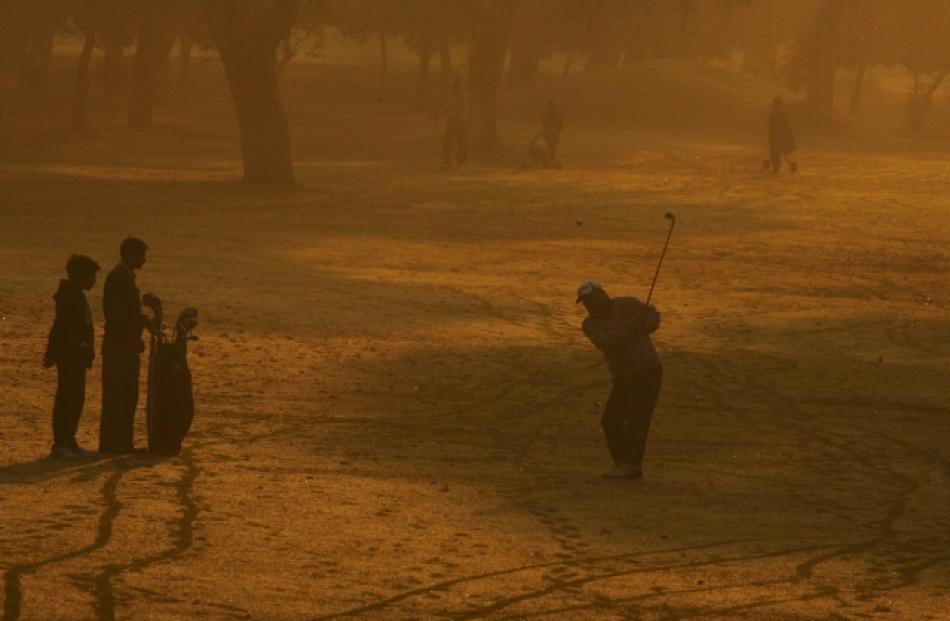 A golfer hits a shot on a driving range amid dense fog during a cold morning in the northern...