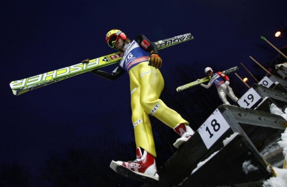 Norway's Tom Hilde (L) and Japan's Taku Takeuchi carry their skis before the trial jump of the...