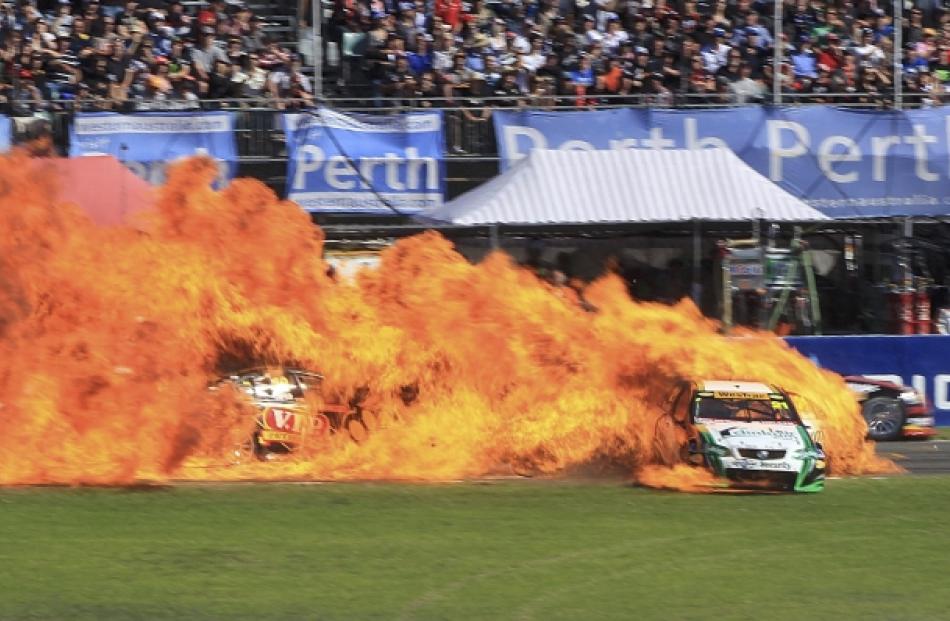 Australian V8 Supercar driver Karl Reindler's car (2-R) bursts into flames after a collision with...