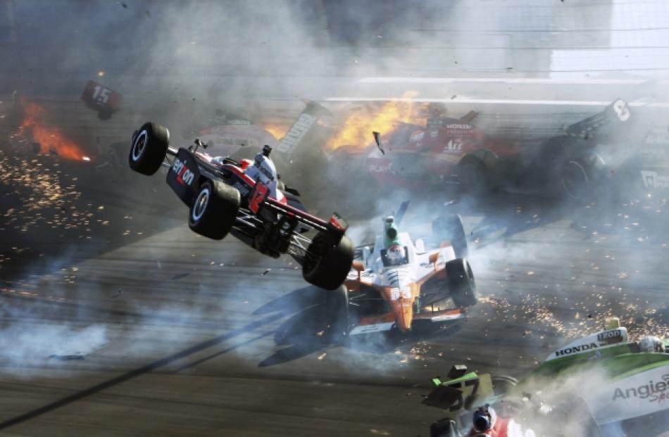 The car of driver Will Power (L) goes airborne during a crash in which driver Dan Wheldon was...