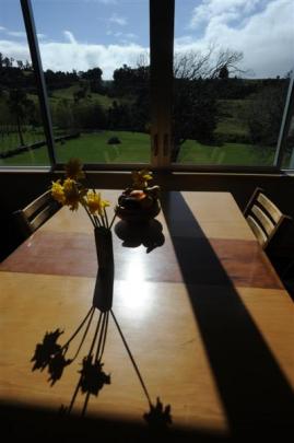 A restored kauri dining table catches the sunlight and rural vista from Jan and Roy Johnstone's...