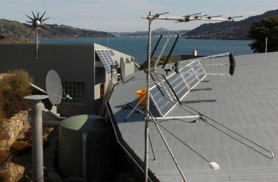 Solar panels adorn the roof, with a rainwater collection tank at left and a small home-made...