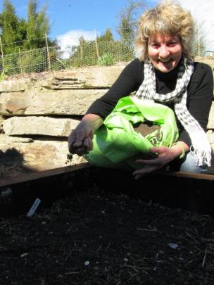Pauline Bastion pours Lloyd Thayer's vermicast on her garden.