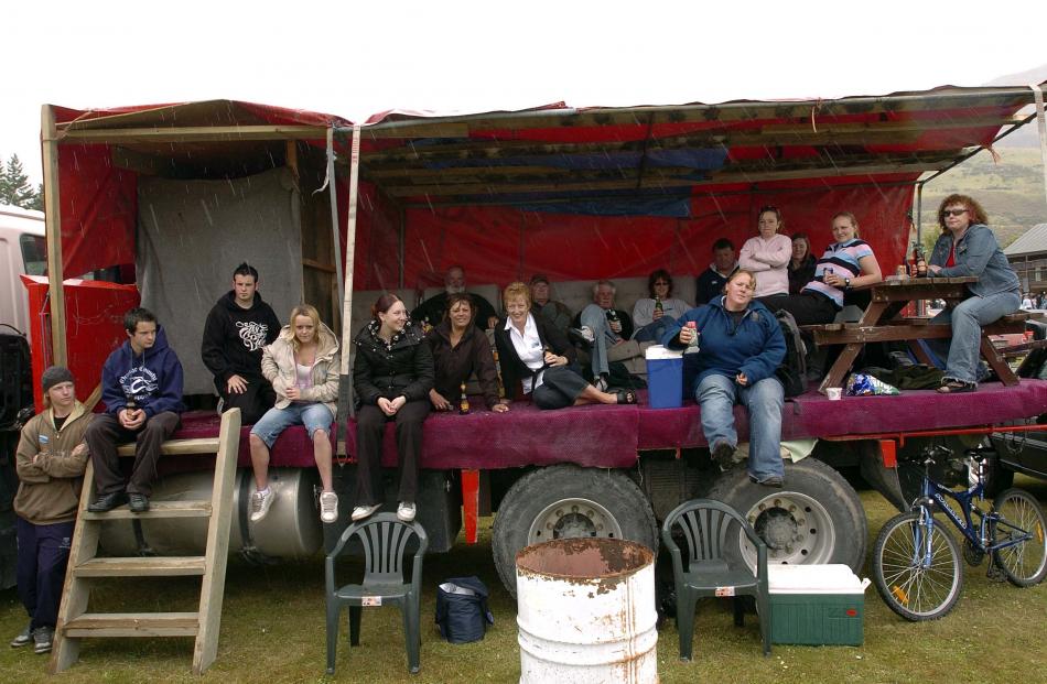 Race-goers shelter from the rain in a truck.