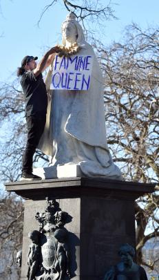 Dunedin protester Andrew Tait places a necklace of potatoes around the Queen Victoria statue at...