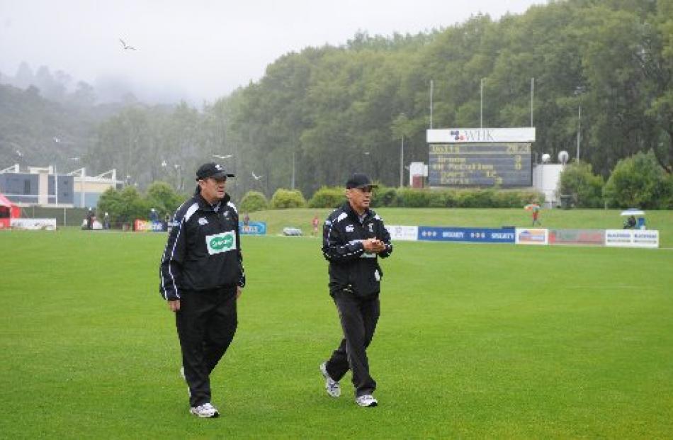 Umpires Gary Baxter (left) and Barry Frost walk off the field during a rain interruption. Photos...