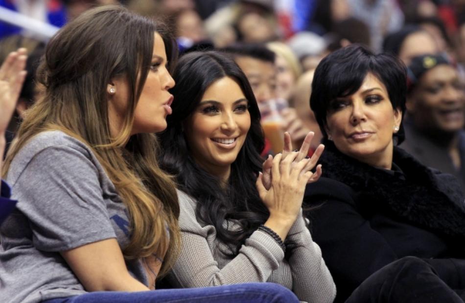 Khloe Kardashian (L) sits next to her sister Kim Kardashian (C) and mother Kris Jenner during an...