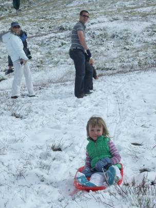 Scarlett Lynas (4), of Auckland, gets up some speed on a borrowed toboggan at Coronet Peak,...