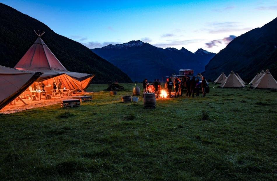 New Zeal clients eating dinner cooked by an on-site chef in a giant Nordic tipi in a remote...