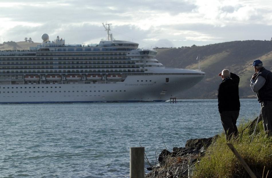 Two men watch the cruise ship Diamond Princess slip past Harington Point last week.