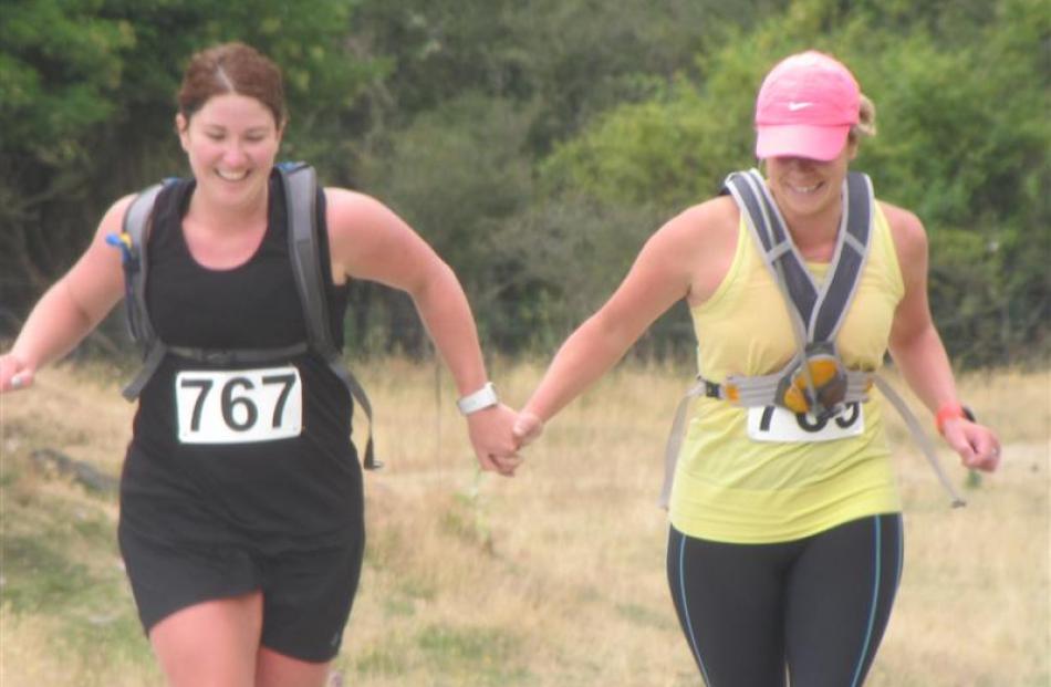 Olivia Caldwell (left) and Bex Harrex, both of Queenstown, hold hands as they near the finish...