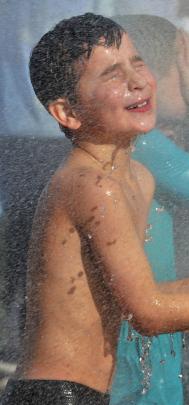 Hudson Scott (7) warms up in a spray of water from a fire truck.
