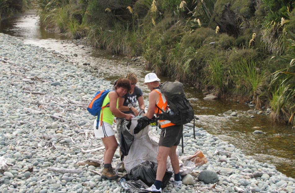 Marietta Gibb, Robyn Hoglund and Robin Manera fill a fadge with rubbish between Barn Bay and...