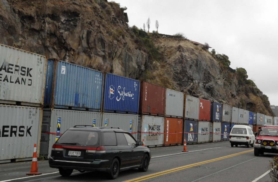 Shipping containers line the road to Sumner to protect against rock falls.