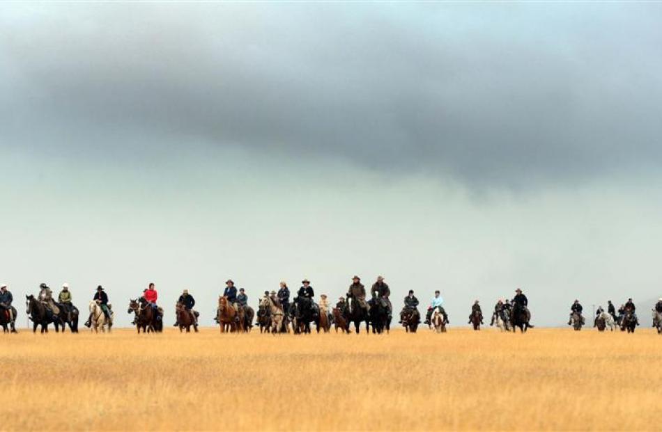 Gathering  storm clouds threaten to drench riders on Twin Peaks Station, south of Omarama, as...