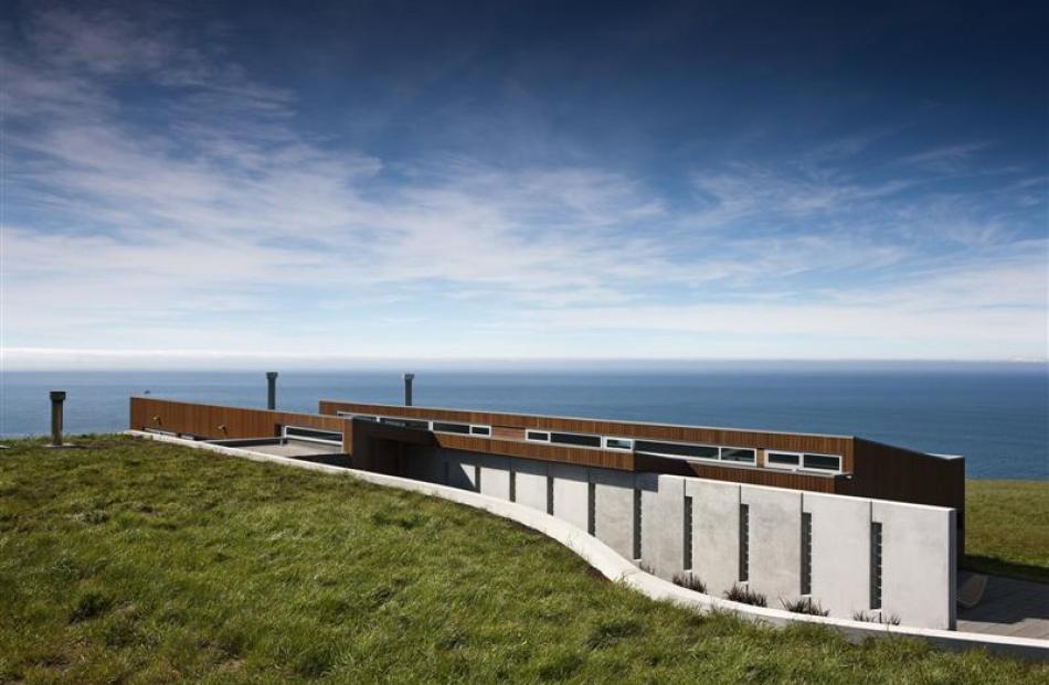 The house links to a dramatic curving retaining wall that houses the garage and creates a series...