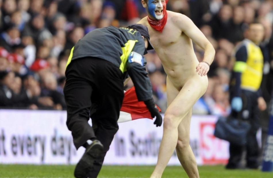 A steward tackles a streaker during the Six Nations rugby match between Scotland and France at...