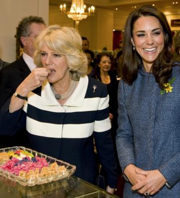 Britain's Catherine, Duchess of Cambridge (R) smiles as Camilla, Duchess of Cornwall tries some...