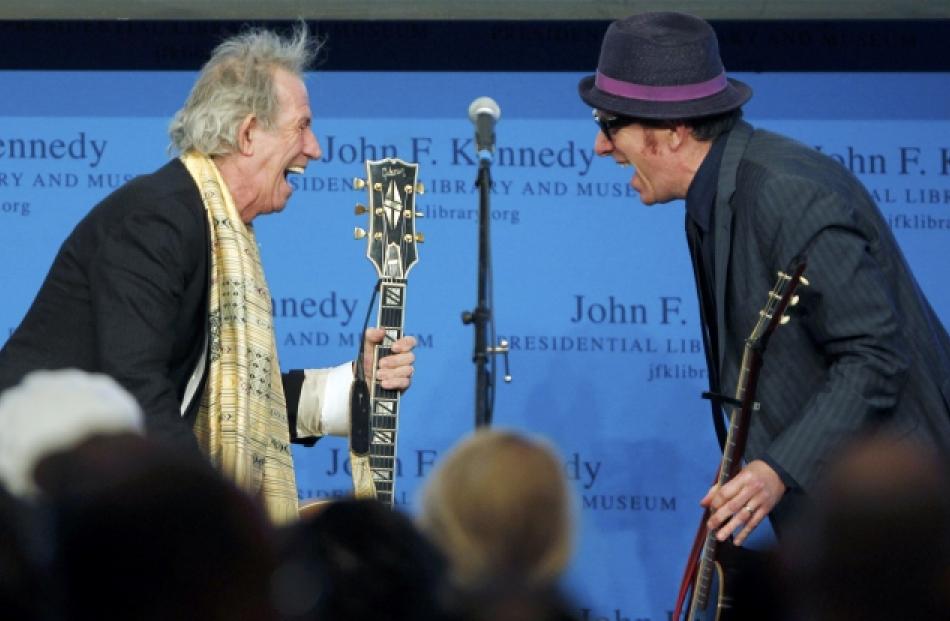 Musicians Keith Richards (L) and Elvis Costello share a laugh as they perform during the 2012...