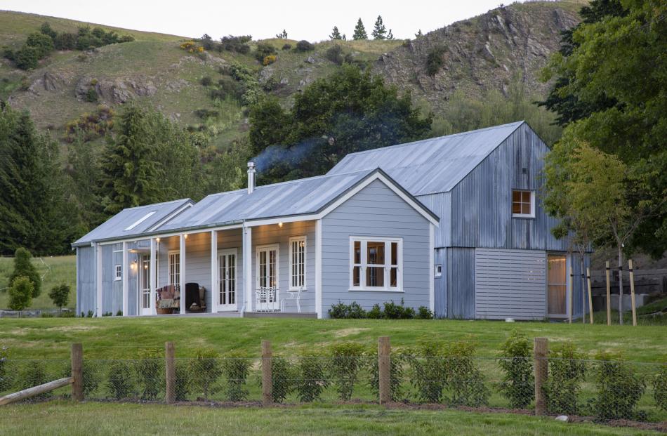 A restored weatherboard cottage, containing the main living areas,  sits in front of a new, two...